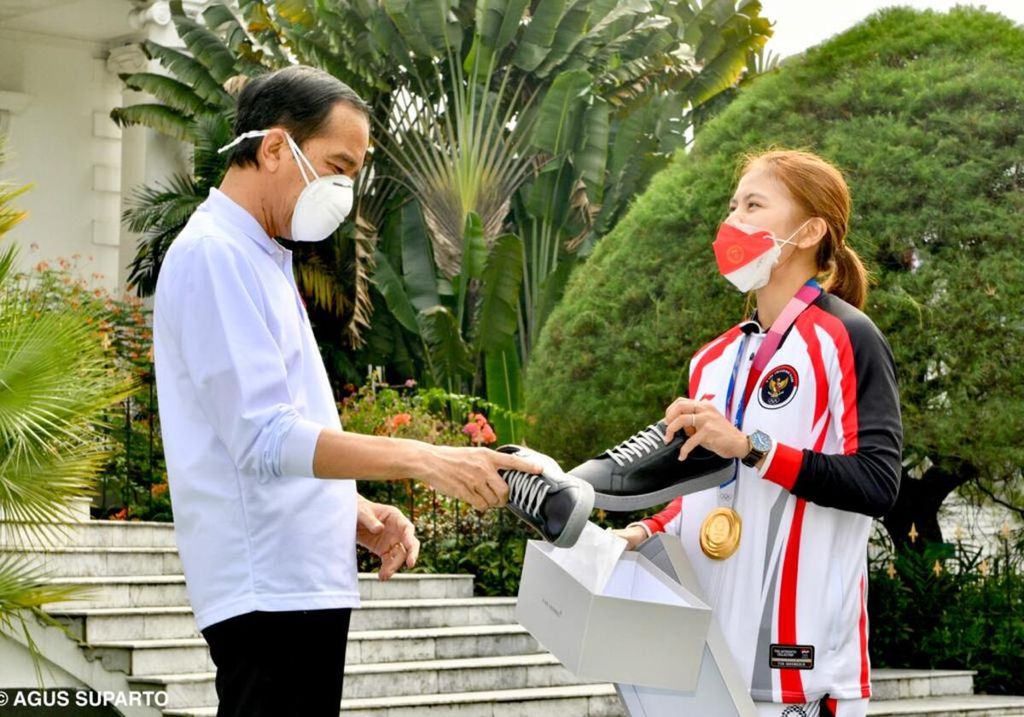 Presiden Joko Widodo berbincang dengan atlet peraih medali emas bulu tangkis di Olimpiade Tokyo 2022, Greysia Polii, pada Agustus 2021. Dalam perbincangan itu, Greysia memperkenalkan produk sepatu yang dijadikan usahanya menyambut pensiun.