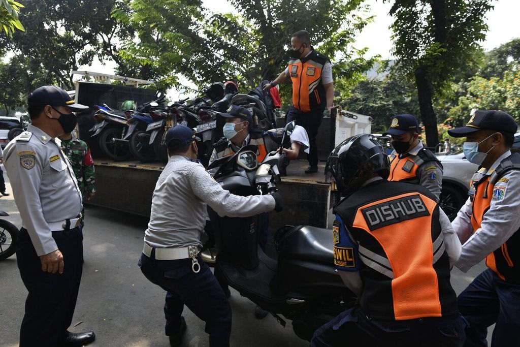 Sejumlah petugas Suku Dinas Perhubungan memindahkan sepeda motor yang terkena razia penertiban parkir liar kendaraan di kawasan Senen, Jakarta Pusat, Rabu (2/6/2021). Dalam razia itu, puluhan sepeda motor yang diparkir di bahu jalan diangkut petugas menggunakan sejumlah truk. Meski berulang kali dilakukan penertiban, parkir liar tetap marak dan banyak dijumpai di sejumlah lokasi di Jakarta. 