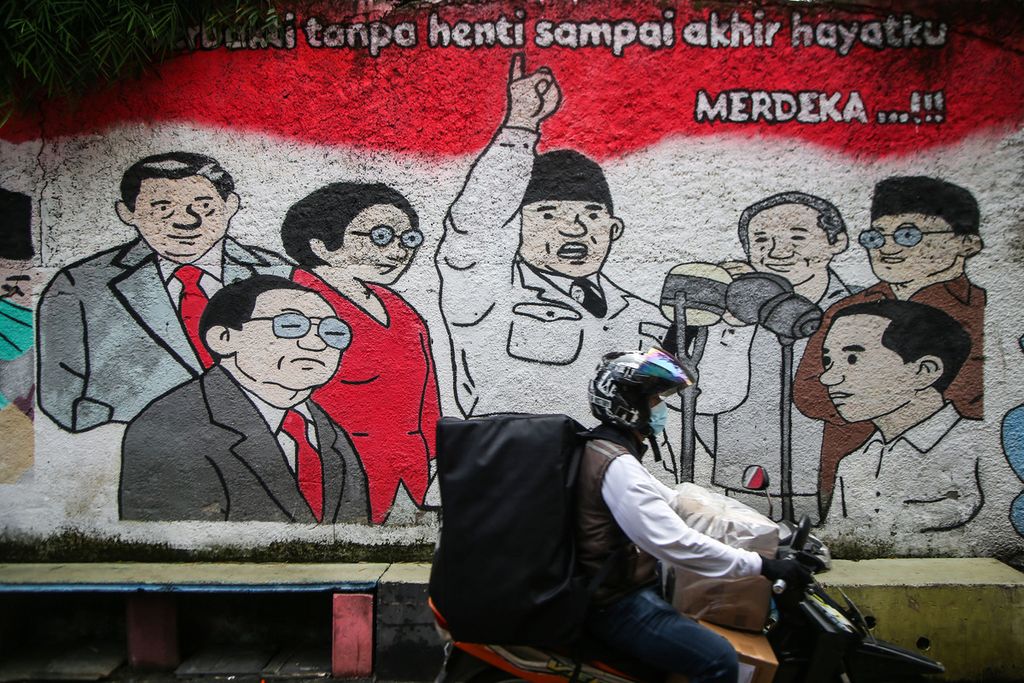 A motorcyclist passes a mural of the seven presidents of the Republic of Indonesia cartoony depicted on a wall in the Pisangan area, South Tangerang, Banten, Sunday (11/14/2021).