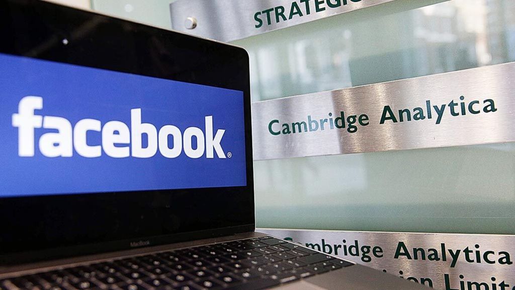 Laptop yang menunjukkan logo Facebook diletakkan di depan tanda penunjuk kantor Cambridge Analytica di luar gedung kantor perusahaan tersebut di London, Inggris, 21 Maret 2018.
