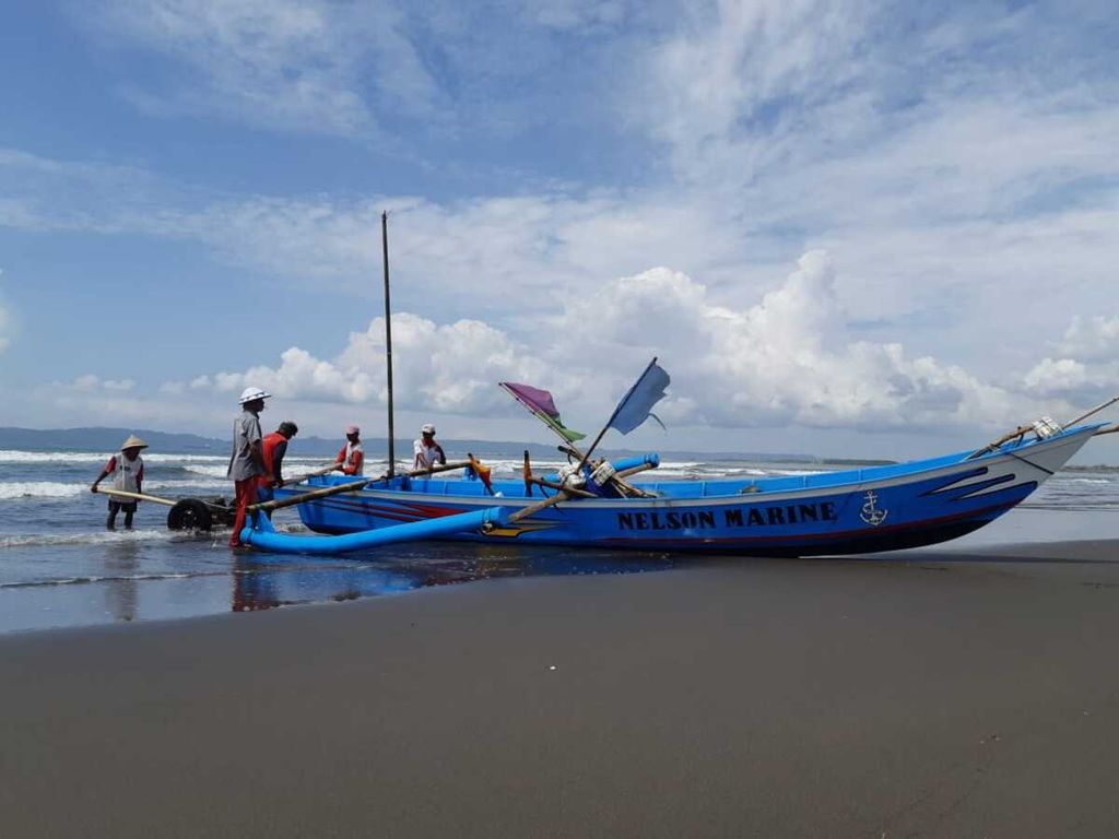 Sejumlah orang mengangkat dan bersiap mendorong perahu ke darat di Pantai Menganti, Kesugihan, Cilacap, Jawa Tengah, Rabu (28/10/2020).