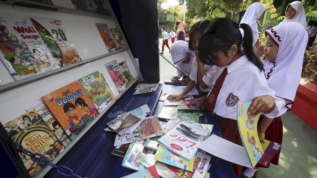 Siswa membaca buku-buku yang tersedia di motor perpustakaan keliling di SD Negeri 02 Malakasari, Jakarta Timur, Selasa (8/1/2019). Layanan perpustakaan keliling ini menjadi sarana yang dinanti para siswa untuk membaca buku-buku baru dan menambah pengetahuan.