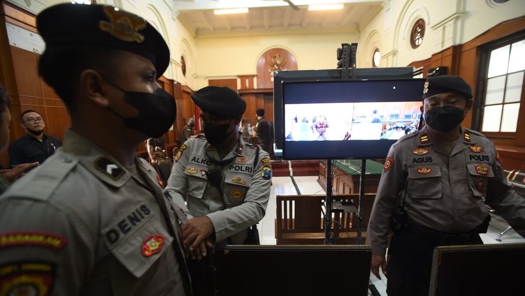 Polisi berjaga saat berlangsung sidang perdana kasus Tragedi Kanjuruhan di Pengadilan Negeri Surabaya, Jawa Timur, Senin (16/1/2023). Sidang dilakukan secara daring dengan diikuti para terdakwa dari dalam Rutan Polda Jatim. 