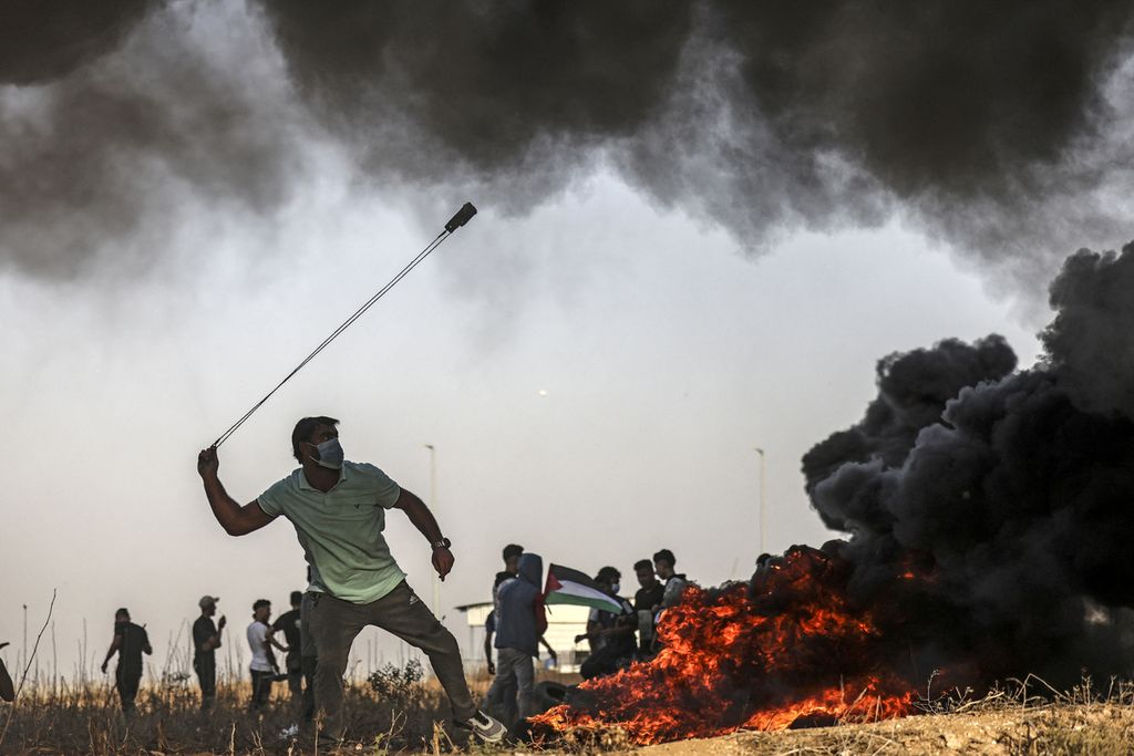 Seorang warga Palestina menggunakan ketapel melontarkan batu melewati perbatasan dengan Israel di Jalur Gaza, Selasa (25/10/2022). 