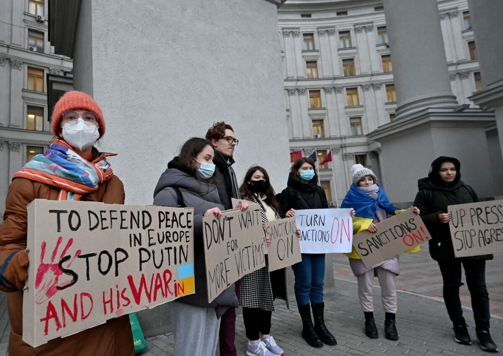 Pengunjuk rasa membawa poster berisi kecaman terhadap Presiden Rusia Vladimir Putin dan negaranya dalam unjuk rasa di luar kantor Kementerian Luar Negeri Ukraina di Kyiv, Ukraina, Senin (21/2/2022). 
