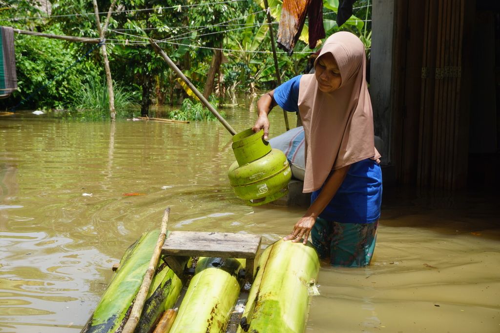 Banjir merendam Desa Nusadadi, Kecamatan Sumpiuh, Banyumas, Jawa Tengah, Jumat (18/3/2022). Sekitar 20 warga mengungsi ke tempat aman. Tampak seorang ibu sedang membeli gas untuk memasak di tengah banjir.