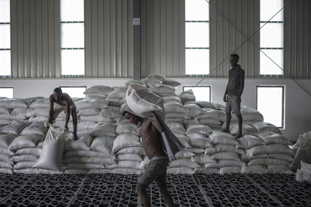 Pekerja mengangkut karung-karung berisi gandum ke truk di gudang Perserikatan Bangsa-Bangsa di Semera, Provinsi Afar, Etiopia, pada 15 Mei 2022. Konflik yang berkecamuk di Etiopia sejak akhir 2020 mengakibatkan jutaan orang kelaparan.    