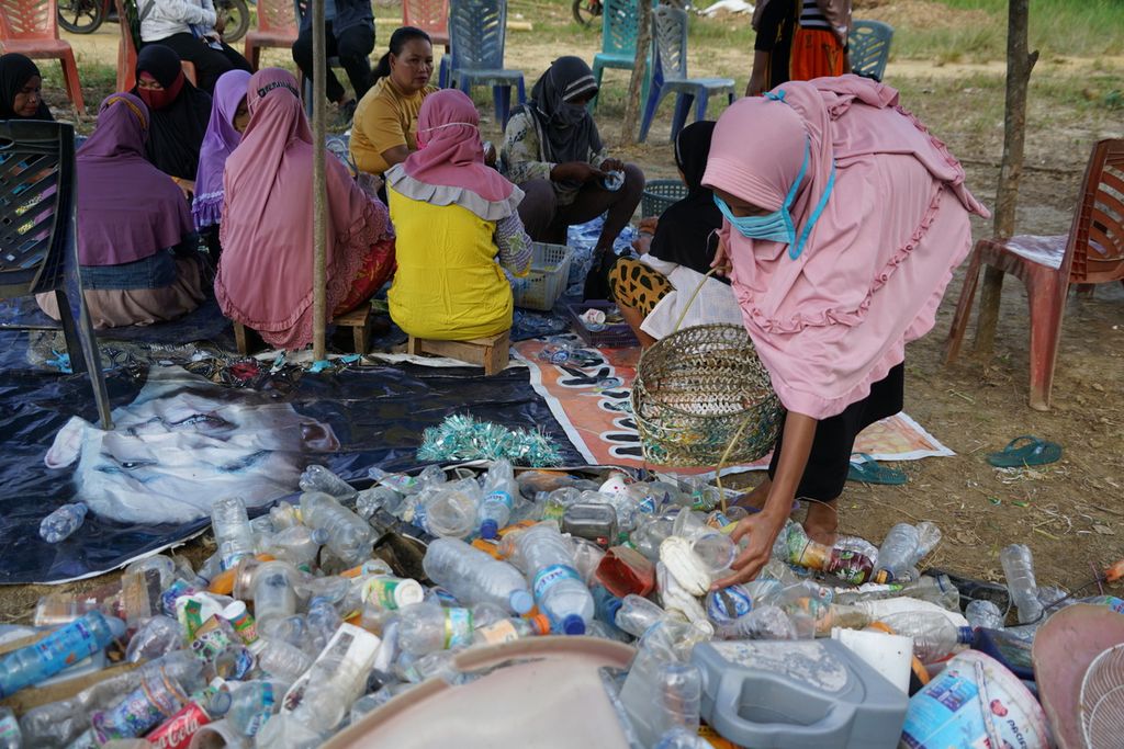 Ibu-ibu hingga nenek-nenek mengolah sampah menjadi kerajinan di Lapulu, Kendari, Sulawesi Tenggara, Sabtu (27/3/2021). Kelompok bank sampah Jaringan Perempuan Pesisir ini mengolah sampah hasil memulung untuk kelestarian lingkungan dan kesejahteraan anggota.