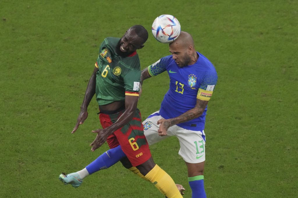 Kapten Brasil, Dani Alves (kanan), berebut bola dengan pemain Kamerun, Nicolas Moumi Ngamaleu, dalam pertandingan terakhir Grup G Piala Dunia 2022 di Stadion Lusail, Qatar, Sabtu (3/12/2022) dini hari WIB. Brasil yang menurunkan pemain lapis kedua kalah oleh Kamerun 1-0. Meski menang, Kamerun gagal melaju ke babak 16 besar.