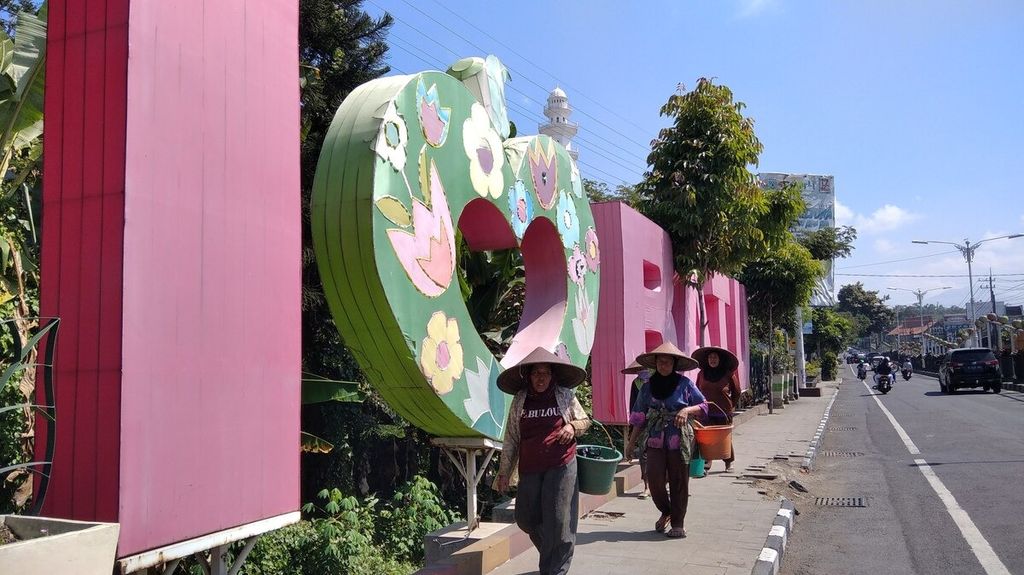 Tiga petani hortikultura tengah berjalan di trotoar di depan tulisan "I Love Batu" di Kota Batu, Jawa Timur, Juni 2020.