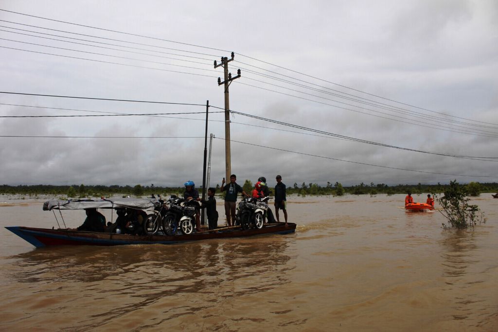 Pengguna jalan Trans-Kalimantan yang menggunakan roda dua menyewa jasa perahu kayu bermotor untuk mengantarkan kendaraan roda dua mereka melewati banjir, di Bukit Rawi, Kabupaten Pulang Pisau, Kalimantan Tengah, MInggu (14/11/2021). 