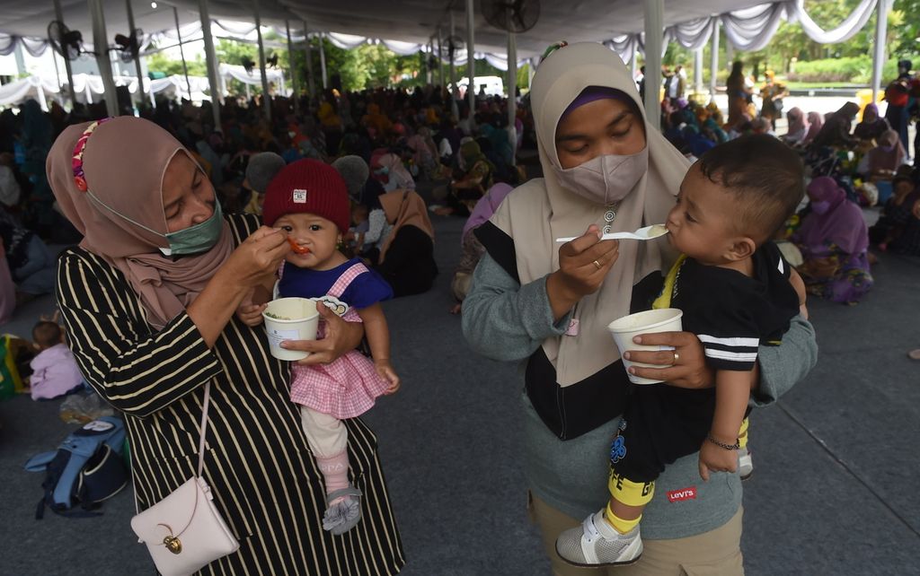 Ibu memberi makan bayinya dengan bubur sehat saat peluncuran Gebyar Lomba Balita Sehat di Halaman Balai Kota Surabaya, Jawa Timur, Rabu (26/1/2022). 
