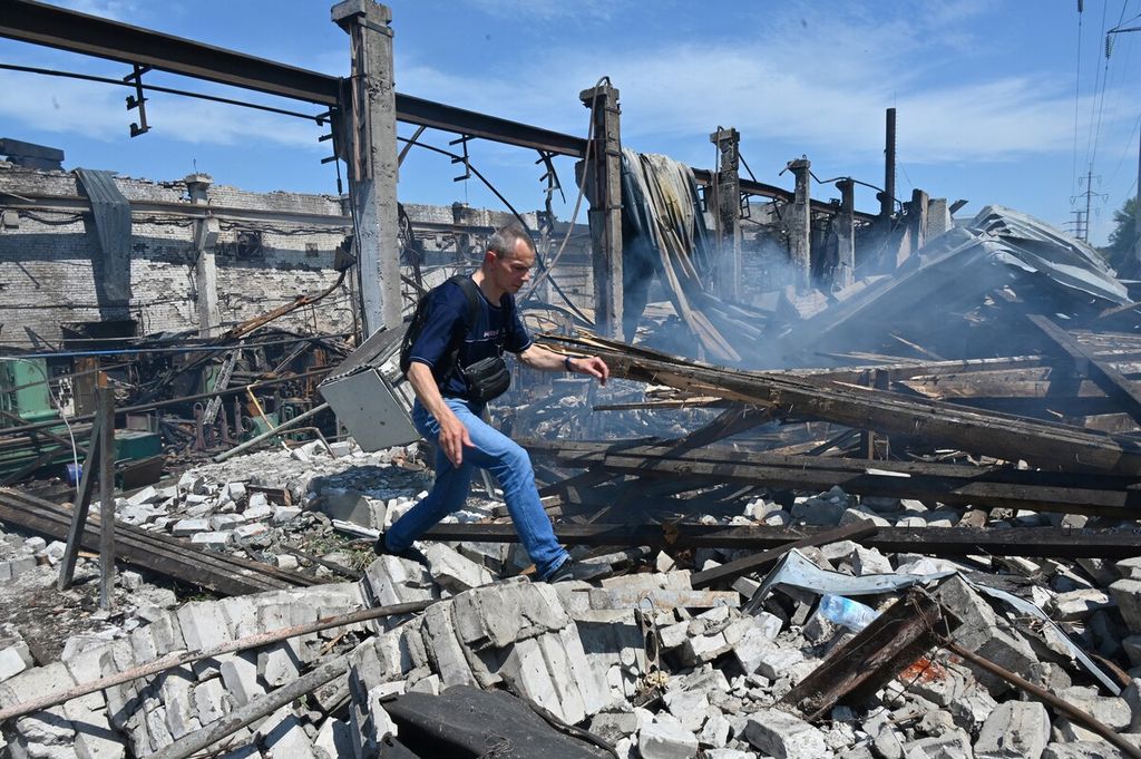 Seorang pria berjalan melintasi reruntuhan gedung di Mashgidroprivod setelah serangan rudal Rusia di Kharkiv, 29 Juni 2022.  