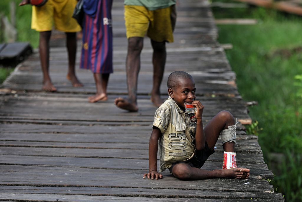Seorang anak asyik memakan mi instan tanpa dimasak terlebih dahulu di Kampung As, Distrik Pulau Tiga, Asmat, Papua, Jumat (15/10/2021).