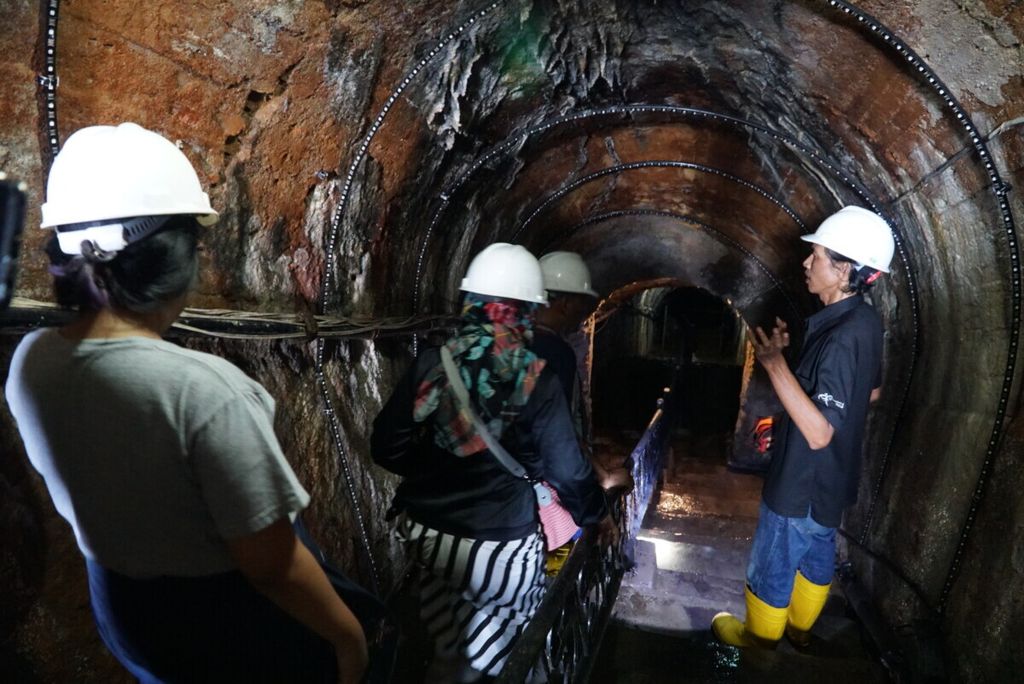 Pemandu wisata (kanan) menjelaskan kepada para pengunjung terkait Lubang Mbah Soero, salah satu lubang tambang peninggalan Tambang Batubara Ombilin di Sawahlunto, Sumatera Barat, Sabtu (29/6/2019). Situs warisan penambangan batubara Ombilin ditetapkan sebagai warisan dunia kategori benda oleh World Heritage UNESCO pada 6 Juli 2019.