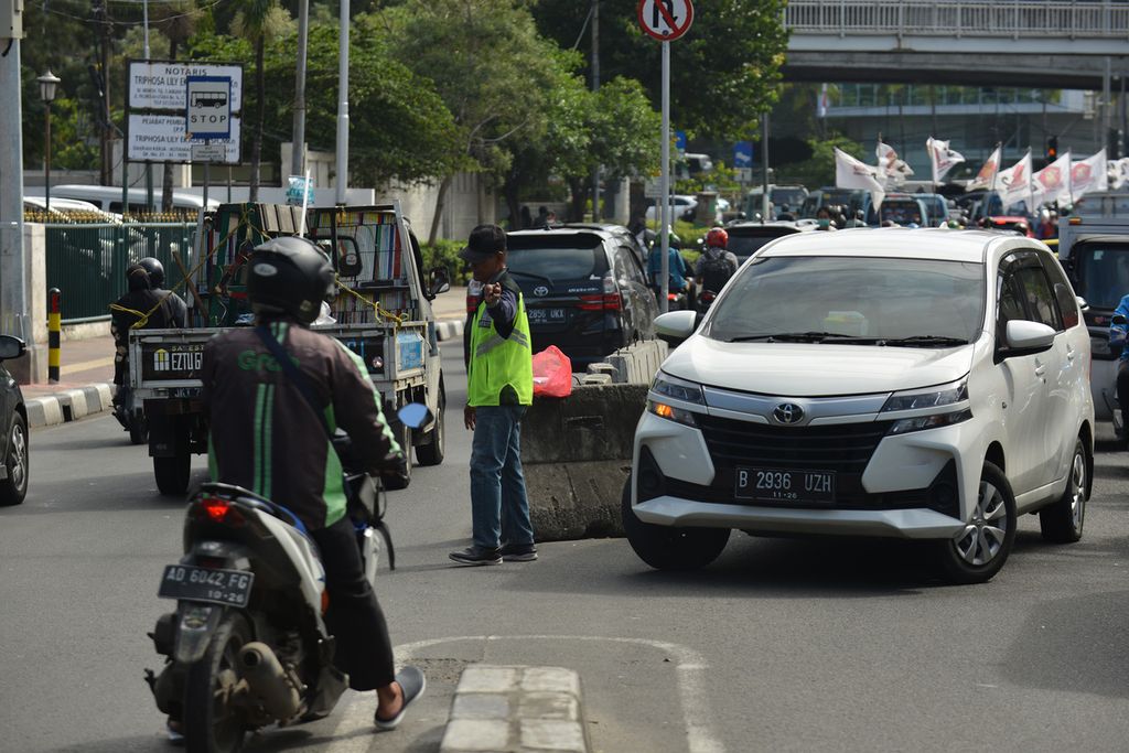 Pengatur lalu lintas liar atau pak ogah mengatur kendaraan yang melintas di Jalan Palmerah Utara, Jakarta Barat, Jumat (10/2/2023). Dinas Perhubungan DKI Jakarta berencana menutup 27 titik putaran balik atau <i>u-turn</i> pada Juni 2023. Penutupan tersebut sebagai usaha pemerintah untuk mengurai kemacetan di Jakarta. Pemerintah juga akan menempatkan petugas di titik-titik putaran balik untuk mengurangi pengatur jalan liar. 