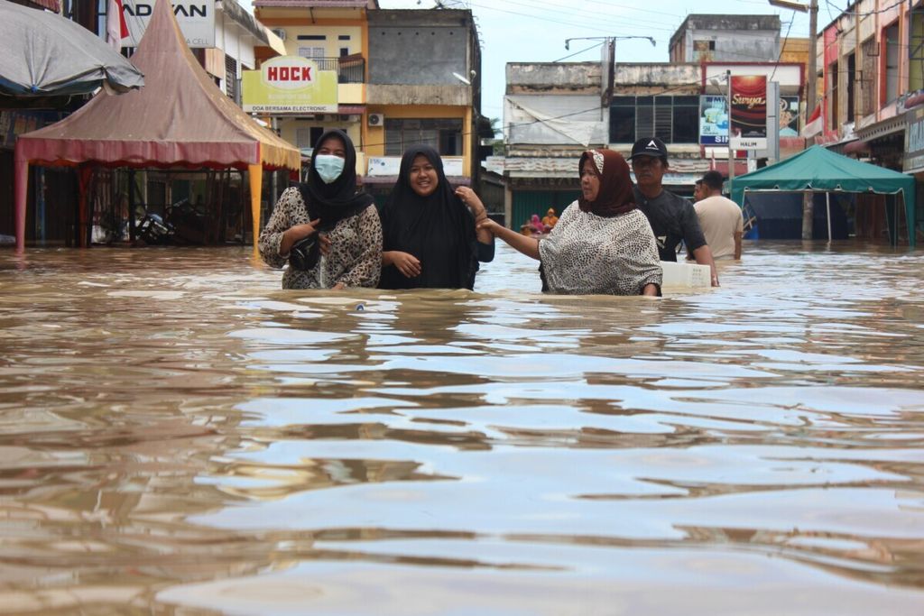 Warga menerobos banjir di pusat perdagangan di Kota Lhoksukon, Kabupaten, Aceh Utara, Aceh, Senin (3/1/2022). Kawasan Lhoksukon nyaris setiap tahun dilanda banjir. Intensitas hujan yang tinggi, kondisi daerah aliran sungai yang kritis, dan deforestasi memicu banjir semakin masif.