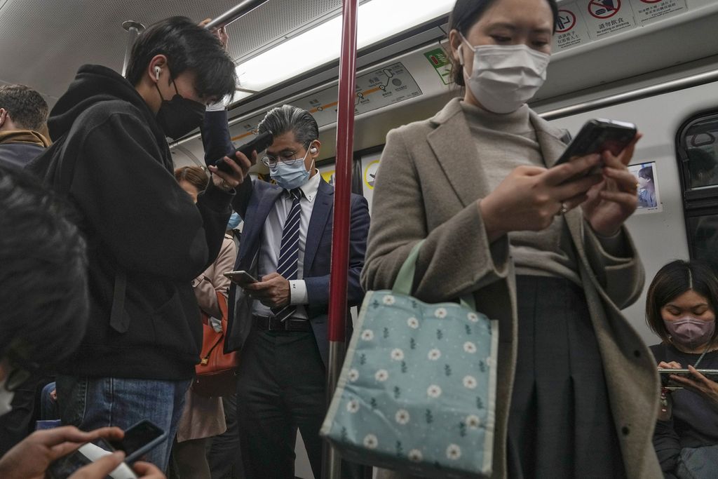 Warga berselancar di telepon seluler masing-masing di kereta bawah tanah di Hong Kong, 7 Februari 2023. Otoritas Hong Kong mencabut aturan wajib bermasker sejak 1 Maret 2023.
