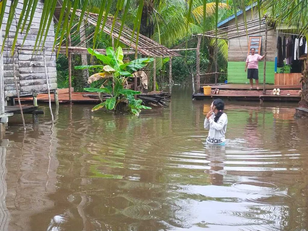 Warga melintasi banjir rob yang melanda Desa Sungai Besar, Kecamatan Lingga Utara, Kabupaten Lingga, Kepulauan Riau, Senin (23/1/2023).