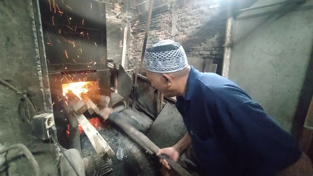 Warkun (58), perajin tahu, tengah menyiapkan api untuk proses merebus kedelai yang akan diproduksi menjadi tahu di rumahnya, Kelurahan Tegal Parang, Kecamatan Mampang Prapatan, Jakarta Selatan, Jumat (2/12/2022).