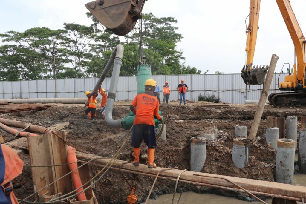 Pekerja memperbaiki pipa PDAM yang rusak akibat pemasangan tiang pancang pembangunan kampus di Surabaya, Senin (18/5/2020).