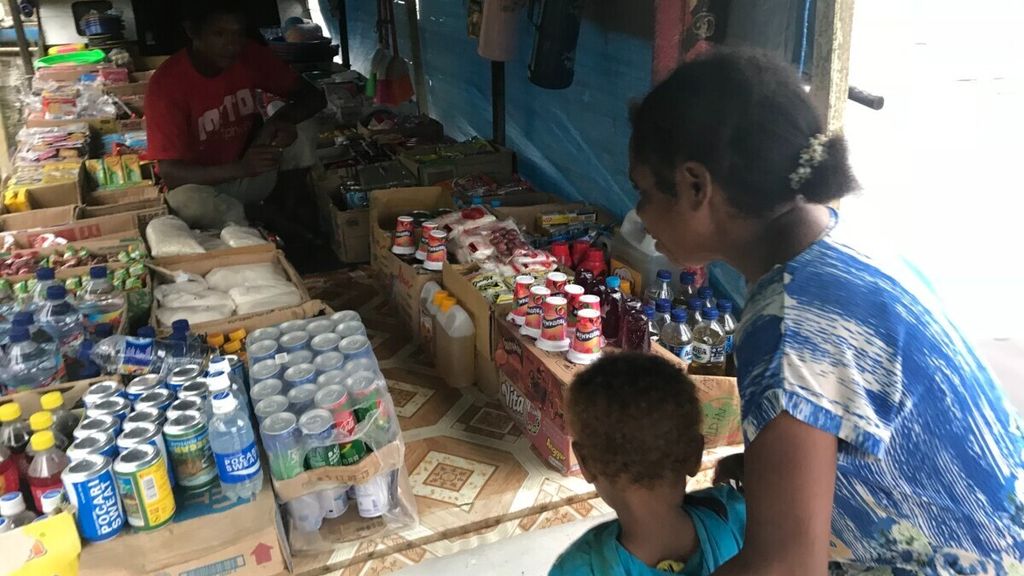 Seorang ibu dan anak di pedalaman Kampung Saga, Sorong Selatan, Papua Barat Daya, membeli makanan instan di <i>jolor-jolor </i>atau warung di atas perahu. Tren global menunjukkan tingkat obesitas lebih tinggi di perdesaan dibandingkan di perkotaan, salah satunya karena kemudahan akses mendapatkan makanan instan. 