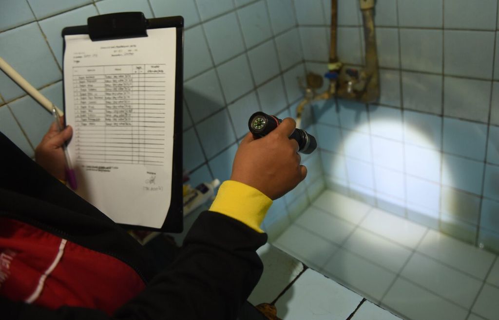 Un oficial de monitoreo de larvas revisa el agua en un baño en RT 002 RW 006, Banyu Urip Village, distrito de Savahan, ciudad de Surabaya, Java Oriental el viernes (17/6/2022). 