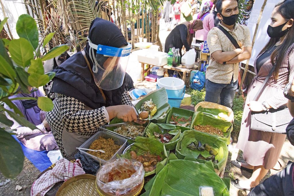 Penjual makanan tradisional mengenakan pelindung wajah ketika melayani pembeli di Pasar Djadoel, Batam, Kepulauan Riau, Minggu (28/6/2020).