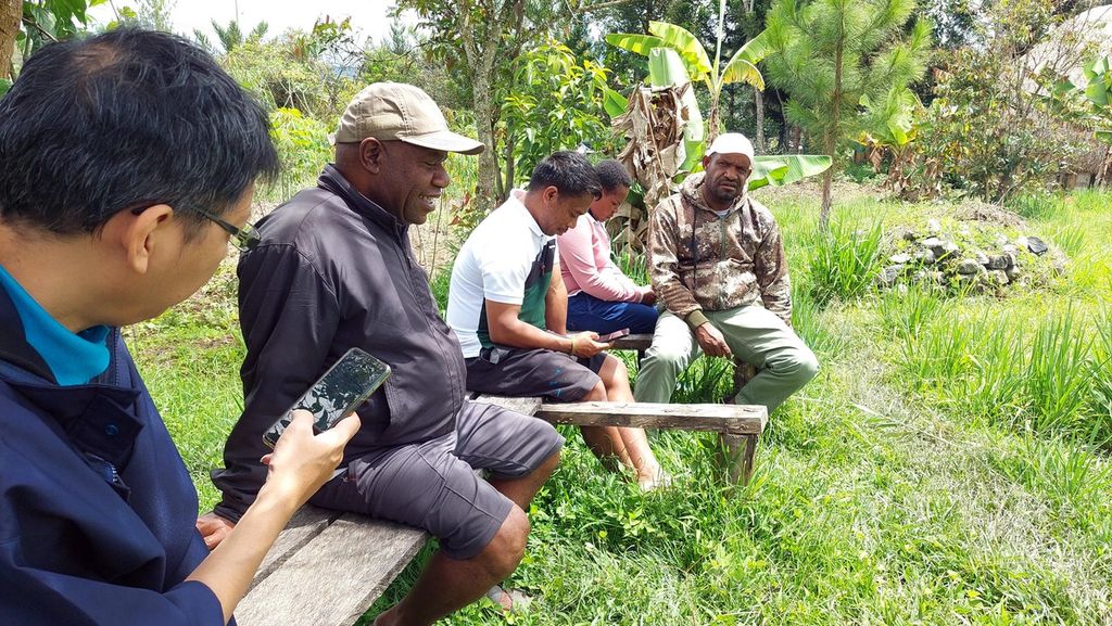 Peneliti Litbang <i>Kompas</i>, Reza Felix (memegang telepon genggam), sedang melakukan wawancara pada responden (jaket hitam, bertopi) di Distrik Pisugi, Kabupaten Jayawijaya, Papua Pegunungan, Senin (30/1/2023).