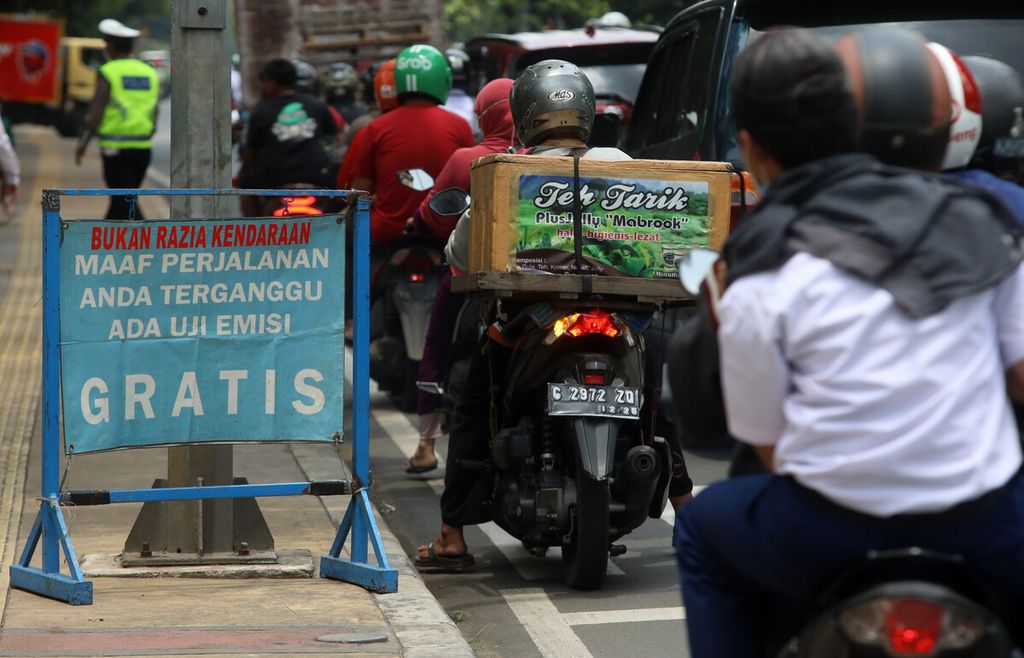 Papan pemberitahuan uji emisi gratis dipasang di pinggir jalan menuju lokasi pengujian di halaman GOR Senam DKI Raden Inten, Jakarta Timur, Selasa (29/3/2022). Uji emisi kendaraan bermotor merupakan salah satu cara menekan laju pencemaran udara dari kendaraan bermotor.