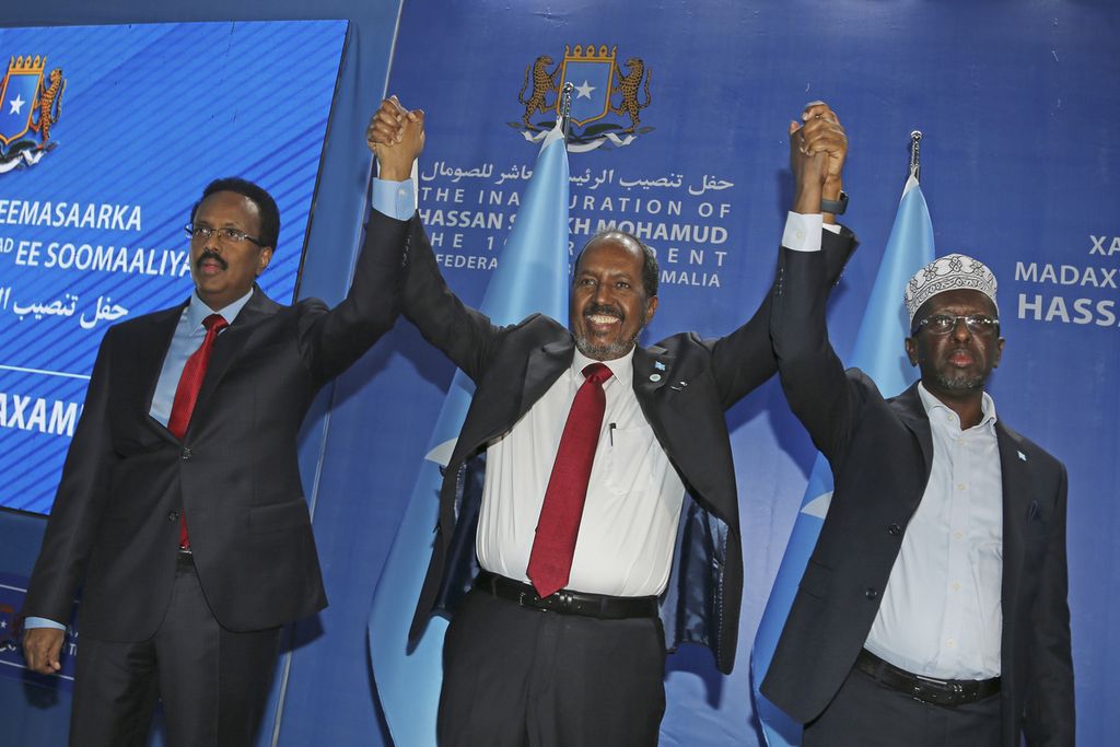 Presiden Somalia Hassan Sheikh Mohamud (tenga), menggandeng tangan mantan presiden Mohamed Abdullahi Mohamed (kiri), dan mantan presiden Sharif Sheikh Ahmed (kanan) saat sesi foto di sela-sela upacara pelantikan presiden di Mogadishu, Kamis (9/6/2022).