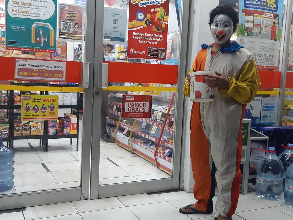 Maulana (21), badut yang tengah menanti pelanggan masuk dan keluar minimarket di Simpang Rawa Belong KH Taisir, Palmerah, Jakarta Barat, Kamis (16/6/2022) malam.