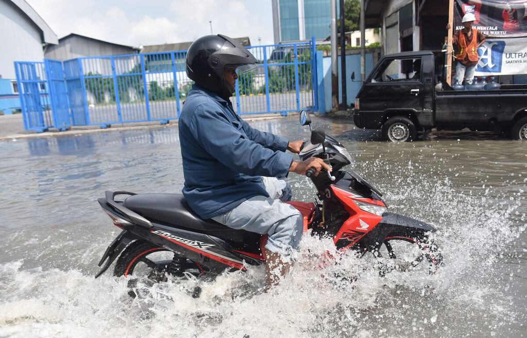Pengendara menerobos banjir rob yang melanda jalan menuju Pelabuhan Ujung, Kota Surabaya, Jawa Timur, Senin (16/5/2022). Rob yang melanda kawasan tersebut mencapai ketinggian 60 cm.