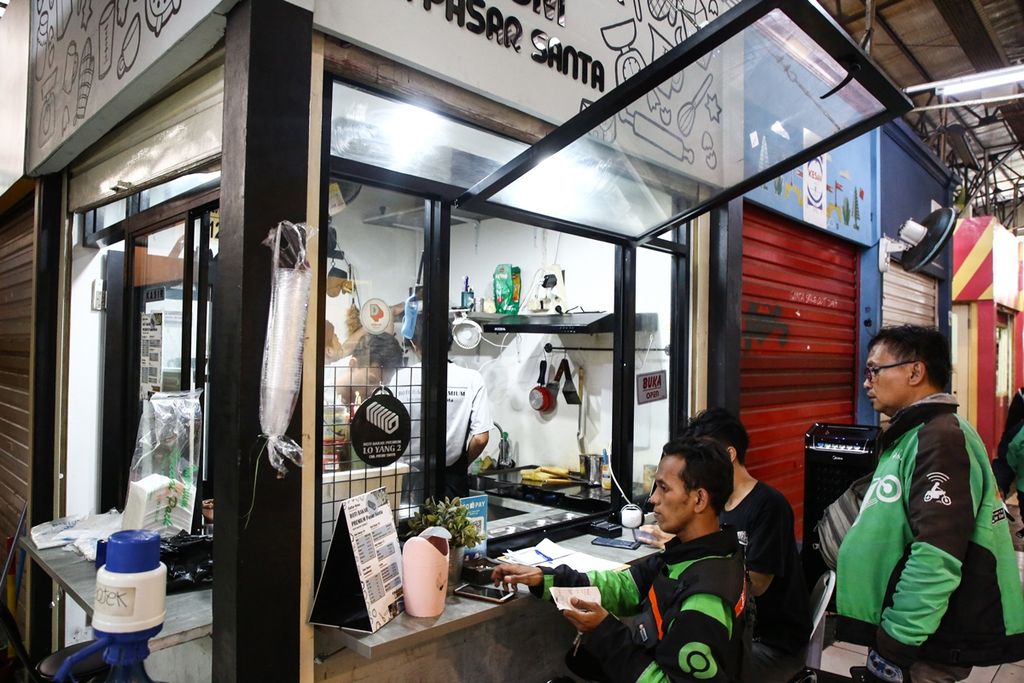 Pengemudi ojek daring memesan makanan untuk pelanggan melalui aplikasi di gerai makanan di Pasar Santa, Kebayoran Baru, Jakarta Selatan, Senin (21/10/2019).