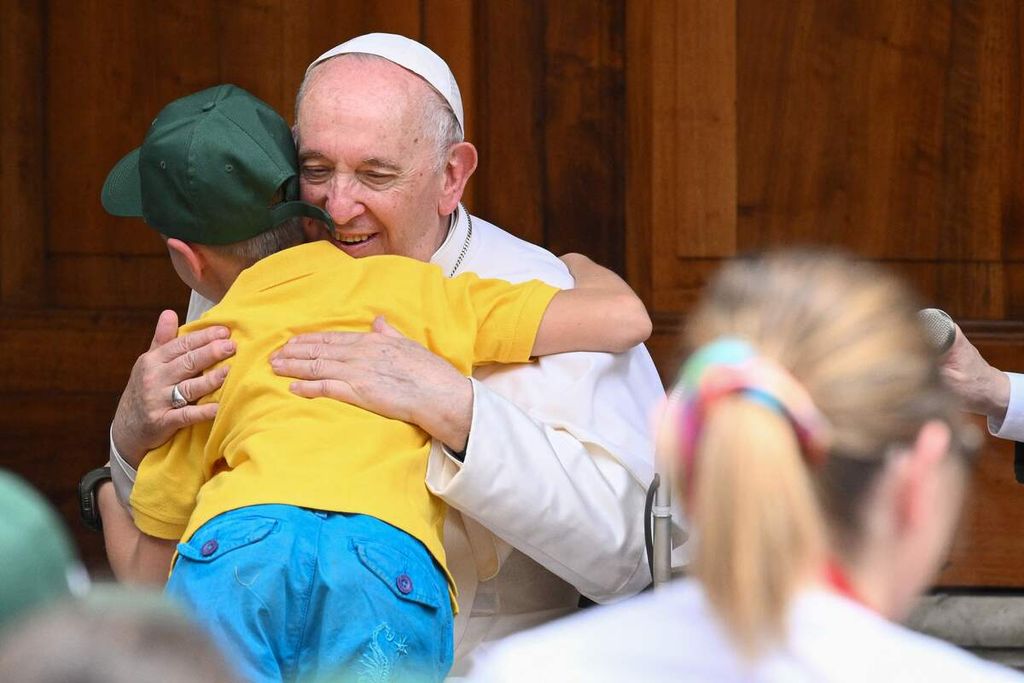 Paus Fransiskus memeluk seorang bocah pengungsi asal Ukraina pada pertemuan "The Cortile dei Bambini" atau Halaman Anak-anak dengan anak-anak yang datang dari seluruh Italia, 4 Juni 2022, di halaman San Damaso di Vatikan. 