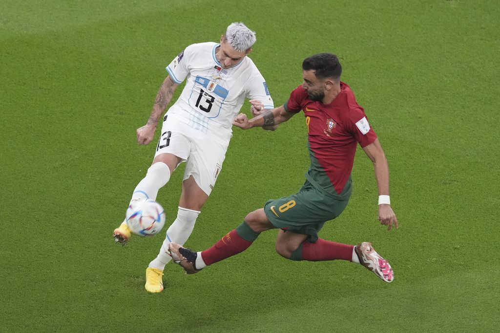 Pemain Portugal, Bruno Fernandes (kanan), berebut bola dengan pemain Uruguay, Guilermo Varela, saat bertanding di fase Grup H Piala Dunia 2022 di Stadion Education City, Qatar, Selasa (29/11/2022).