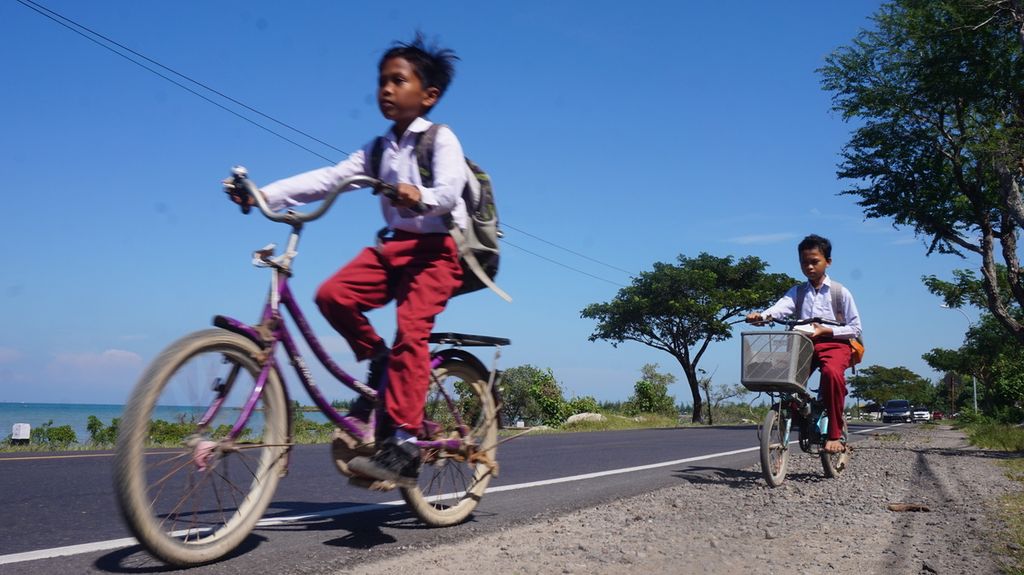 Anak-anak nelayan bersepeda sepulang sekolah di Jalan Raya Pamekasan-Sumenep, Pulau Madura, Jawa Timur, Senin (20/6/2022). Pemerataan pembangunan prasarana dan sarana transportasi serta utilitas, termasuk telekomunikasi, mendorong peningkatan kualitas sumber daya manusia pesisir. Anak-anak nelayan dapat menikmati pendidikan berkualitas setara dengan masyarakat perkotaan.