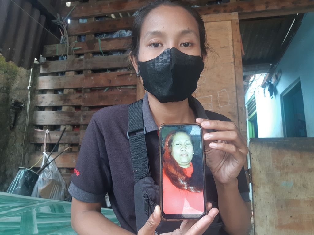 Sri Rejeki (27) menunjukkan potret Sutinih (47), ibunya, di Desa Dadap, Kecamatan Juntinyuat, Kabupaten Indramayu, Jawa Barat (22/1/2022). Selama 13 tahun, Sri tidak berjumpa dengan ibunya yang menjadi pekerja migran di Irak. Keluarga berharap Sutinih segera pulang.