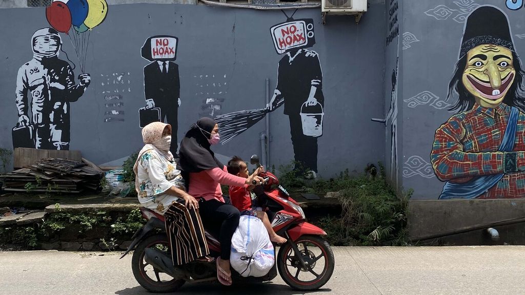 Warga melintasi mural yang dibuat untuk melawan penyebaran informasi palsu di masyarakat (hoaks) di Jalan KH Hasyim Ashari, Tangerang, Banten, Senin (22/2/2021). Pemerintah dan DPR telah memutuskan untuk merevisi UU Informasi dan Transaksi Elektronik (UU ITE). 