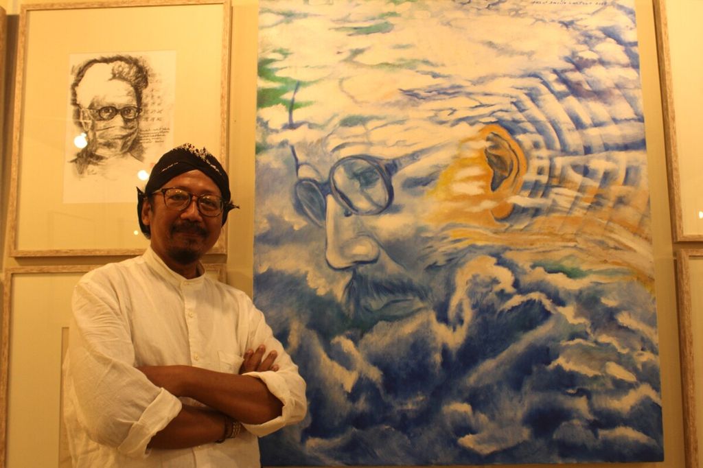 Perupa, penyair, sekaligus jurnalis Yusuf Susilo Hartono dengan latar belakang lukisannya dalam Pameran Retrospeksi 40 Tahun Berkarya Among Jiwo di Museum Nasional Indonesia, Jakarta, Kamis (10/11/2022).