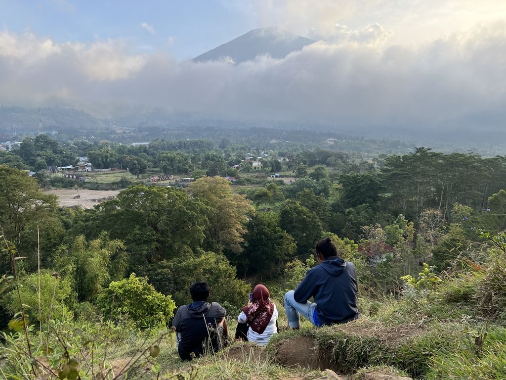 Sejumlah wisatawan menikmati suasana saat Gunung Rinjani tertutup kabut dari Bukit Pegasingan di Desa Sembalun, Kabupaten Lombok Timur, NTB (4/9/2022). Lokasinya yang berada di kaki Gunung Rinjani, membuat Desa Sembalun yang sejak 2016 menjadi desa wisata, 