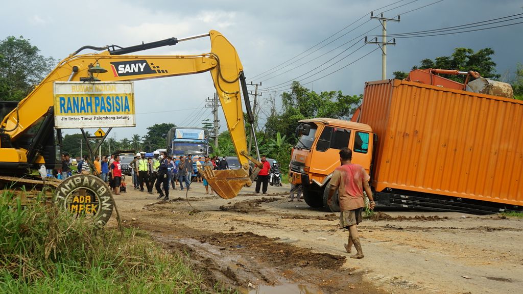 Petugas kepolisian dibantu masyarakat berupaya mengevakuasi sebuah truk tronton yang terperosok di jalan lintas timur Sumatera ruas Palembang-Betung, Sabtu (23/4/2022). 