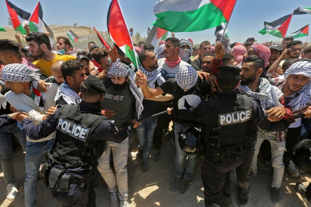 Pengunjuk rasa dari Jordania dan Palestina berdemonstrasi dalam solidaritas untuk warga Palestina di kota Karameh, wilayah yang berbatasan dengan Tepi Barat yang diduduki Israel sejak 1967, pada 15 Mei 2021. 