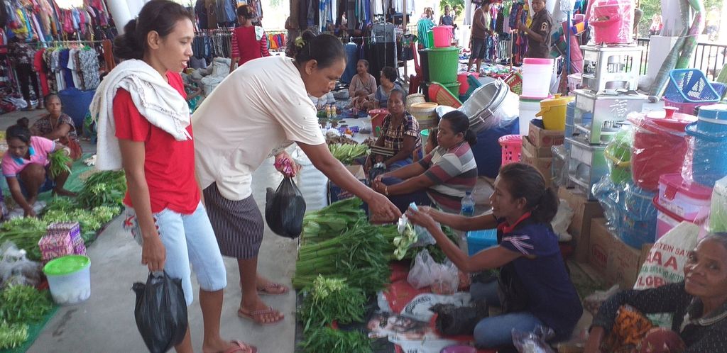 Ibu dan anak dari Timor Leste sedang membeli sayur dari pedagang sayur warga perbatasan Indonesia di Motaain, Rabu (5/2/2020). Mayoritas warga Timor Leste datang ke Pasar Motaain untuk berbelanja sayur, buah, makanan bayi, dan barang elektronik, setelah menukar uang dollar mereka ke mata uang rupiah.