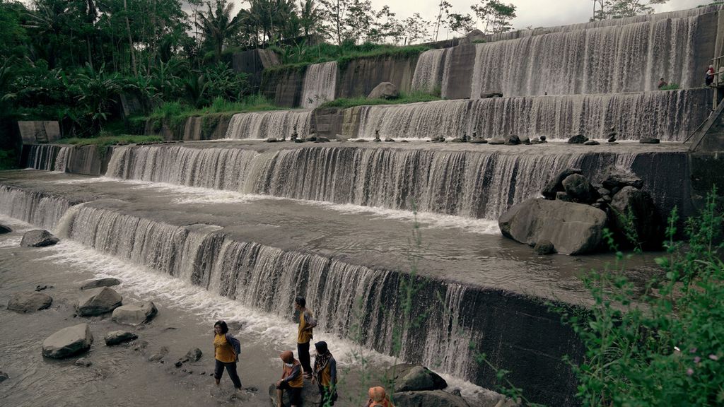 Wisatawan menikmati gemericik air dari Sungai Krasak yang mengalir melewati Grojogan Watu Purbo di Dukuh Bangunrejo, Desa Merdikorejo, Kecamatan Tempel, Kabupaten Sleman, DI Yogyakarta, Rabu (24/3/2021). Grojogan Watu Purbo dengan enam tingkatan ini dibangun tahun 1975 dalam pembangunan sabo dam untuk menahan aliran banjir lahan hujan Gunung Merapi. 