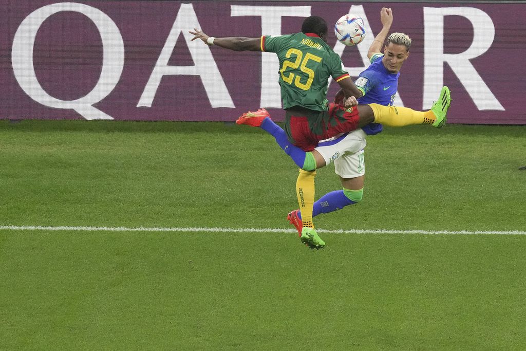 Pemain Brasil Antony berebut bola dengan pemain Kamerun Nouhou Tolo dalam pertandingan terakhir Grup G di Stadion Lusail, Qatar, Sabtu (3/12/2022) dini hari WIB. Brasil yang menurunkan pemain lapis kedua kalah oleh Kamerun 1-0. Meski menang, Kamerun gagal melaju ke babak 16 besar. Brasil lolos bersama Swiss yang pada saat bersamaan menang 3-2 atas Serbia.