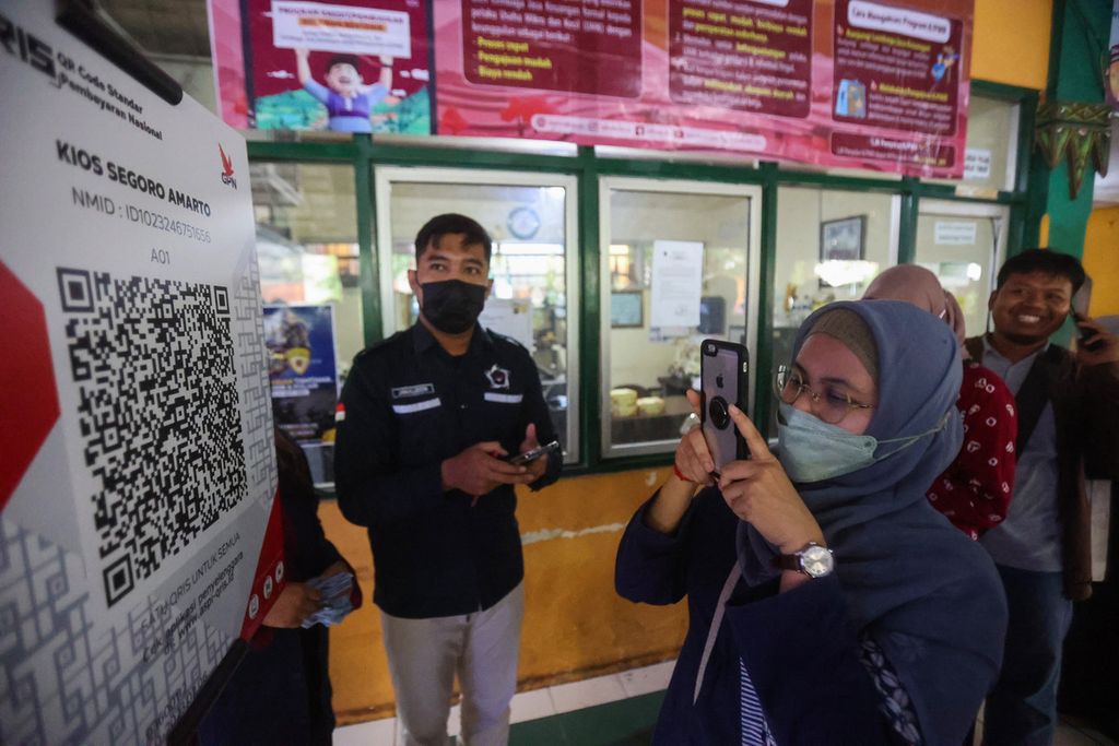 Warga menggunakan QRIS untuk membayar pembelian beras saat acara operasi pasar sekaligus sosialisasi penggunaan QRIS di Pasar Beringharjo, Yogyakarta, Kamis (9/2/2023). 