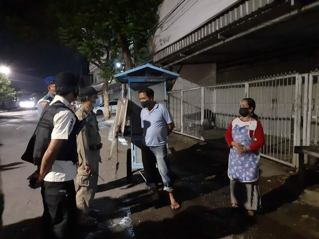 Petugas gabungan mengkampanyekan pemberlakuan pembatasan kegiatan masyarakat (PPKM) darurat kepada penjual makanan minuman yang melewati batas waktu operasional di Surabaya, Jawa Timur, Juli 2021. 