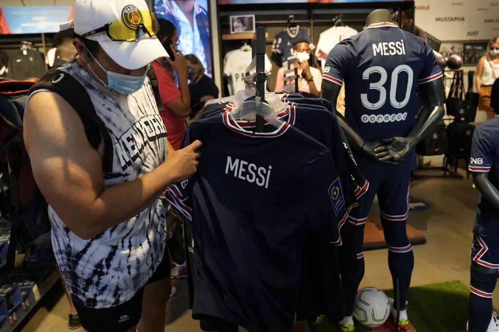 Seorang suporter PSG melihat jersei Lionel Messi di outlet resmi PSG di Paris, Perancis (11/8/2021). Kepindahan Messi ke PSG membuat  jersei dan souvenir Messi banyak dibeli suporter PSG. 