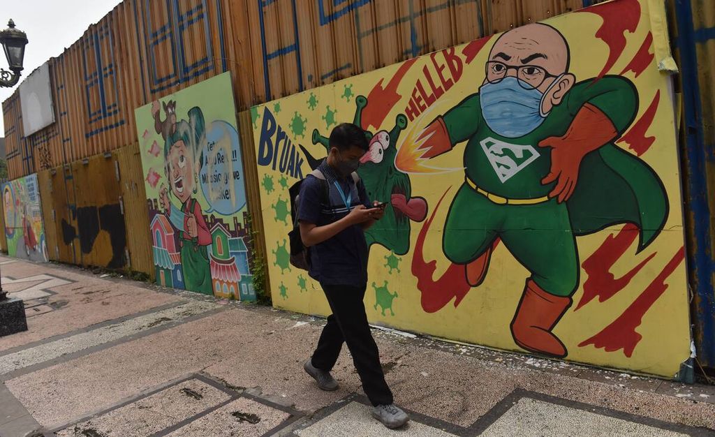 Warga melintas di depan mural bertema protokol kesehatan di Jalan Tunjungan, Kota Surabaya, Jawa Timur, Senin (21/2/2022). Mural yang sejatinya untuk mengingatkan warga agar patuh pada protokol kesehatan banyak dirusak oleh tangan yang tidak bertanggung jawab. 